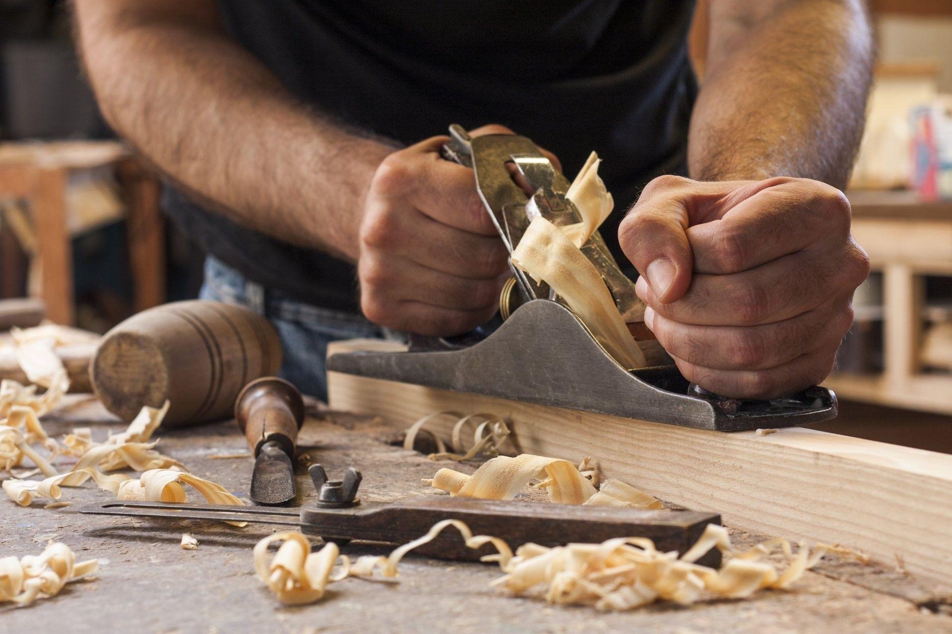 Hands using a hand plane on a board in a woodshop